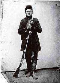 Black and white photo of Private George Fehrenbacher of Company F standing in his Civil War uniform holding a Springfield rifle musket